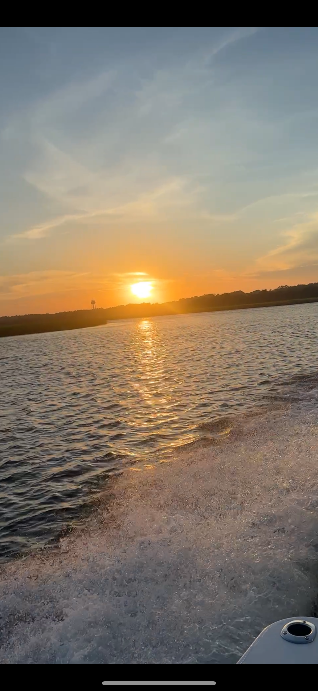 Sunset over an ocean with a boat's wake in the foreground